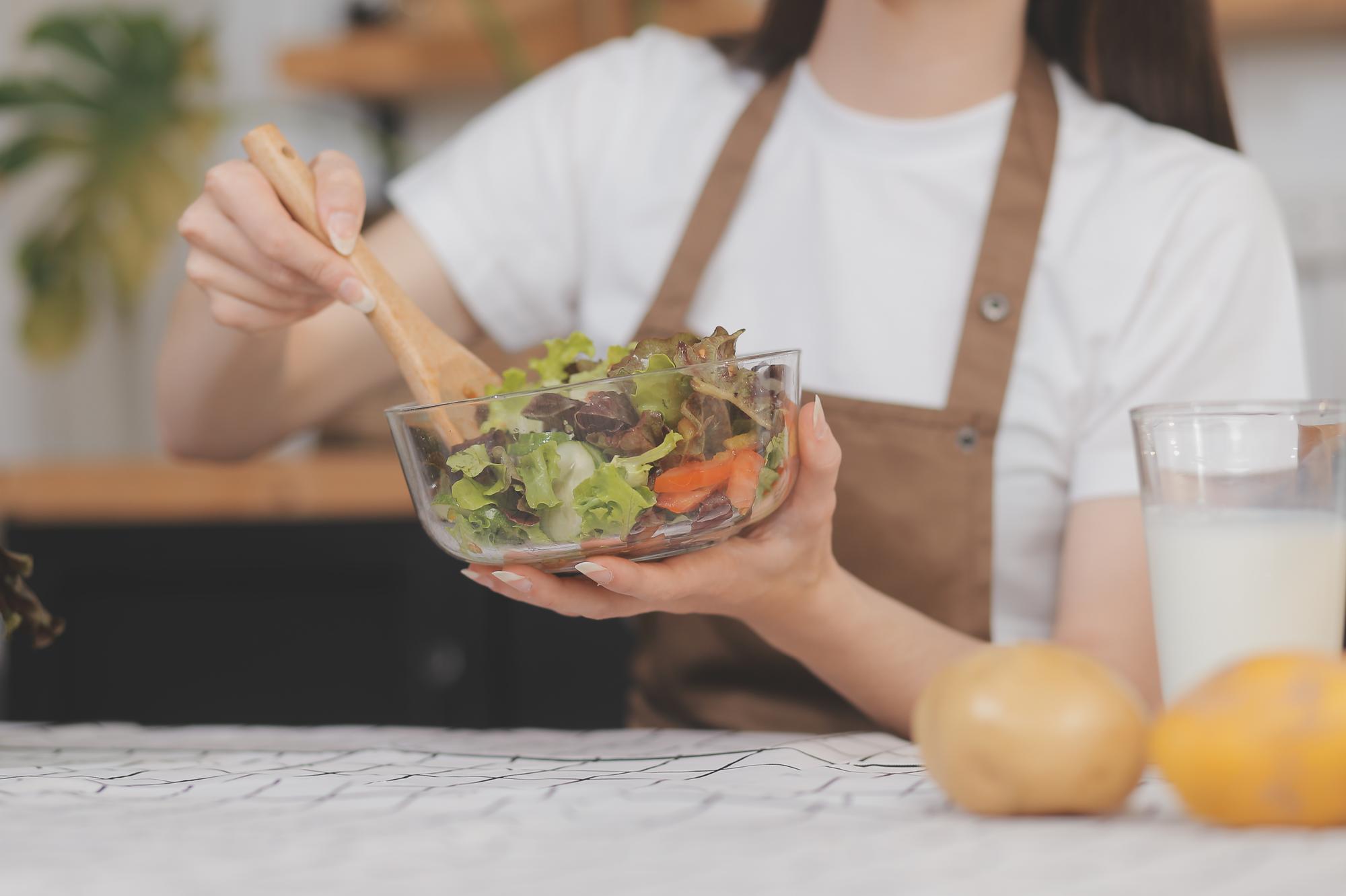 Student plating a simple composed salad in studio light