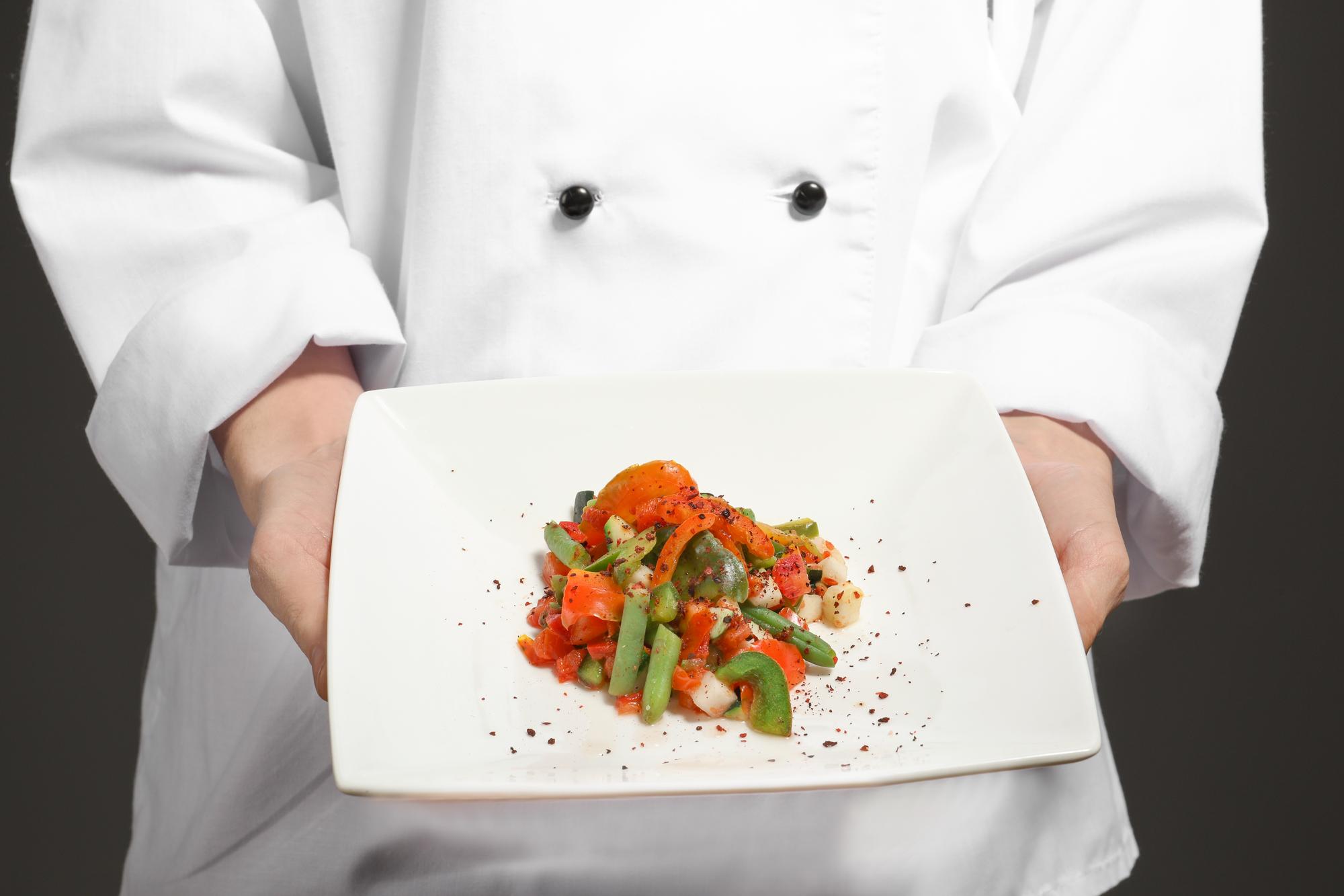 Instructor plating a composed dish on a wooden table